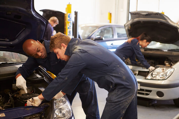 An experienced mechanic giving a budding mechanic hands-on auto mechanic training