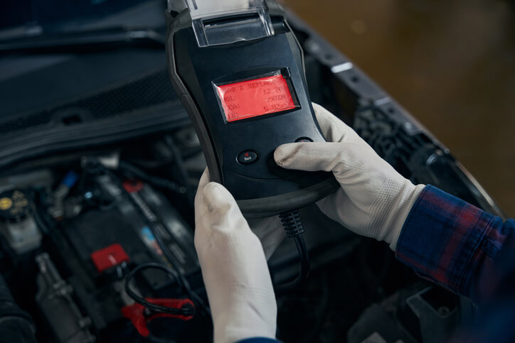 A hybrid and electric vehicle mechanic checking the voltage on an electric vehicle’s battery system