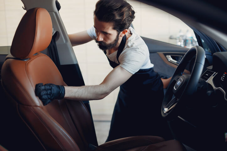 An auto detailing student learning leather conditioning techniques.