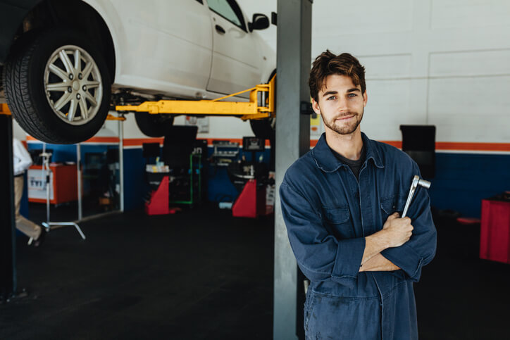 After completing his auto mechanic training, a male auto mechanic apprentice at an auto repair shop.