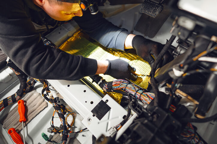 An automotive technician working on sensors and hardware in a self-driving car prototype in automotive technology training