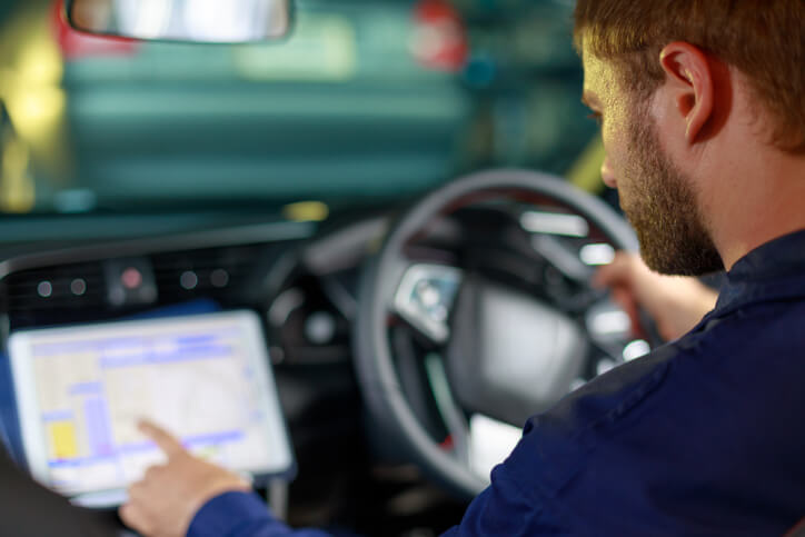 A tech-savvy automotive training student examining a self-driving car’s control panel.