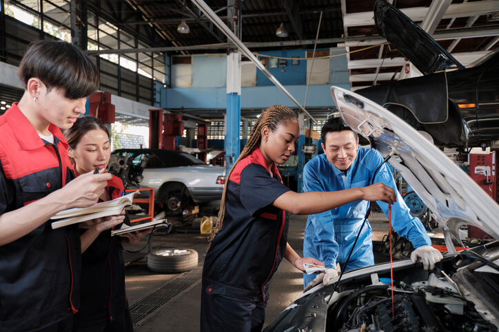 An instructor guiding students through an interactive automotive training session