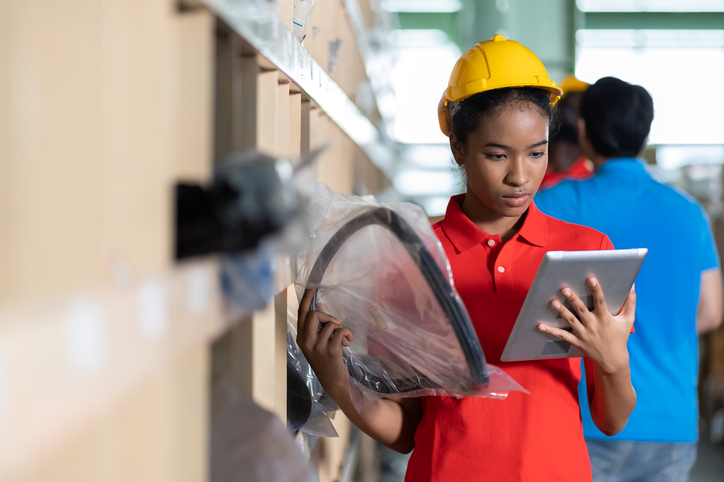 auto parts training grad picking a spare part off a shelf using a tablet